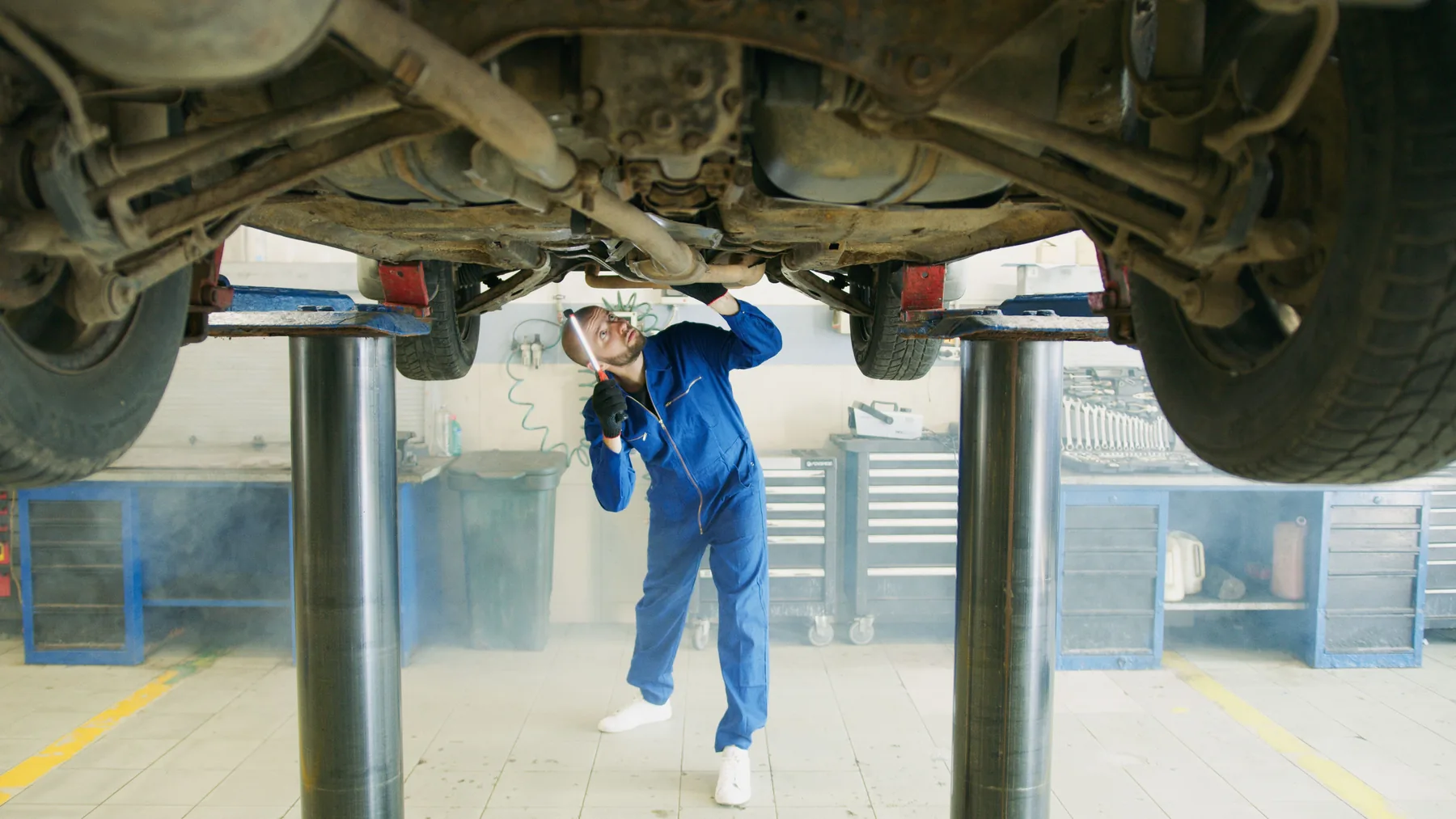 Mechaniker prüft ein Fahrzeug von unten auf einer Hebebühne