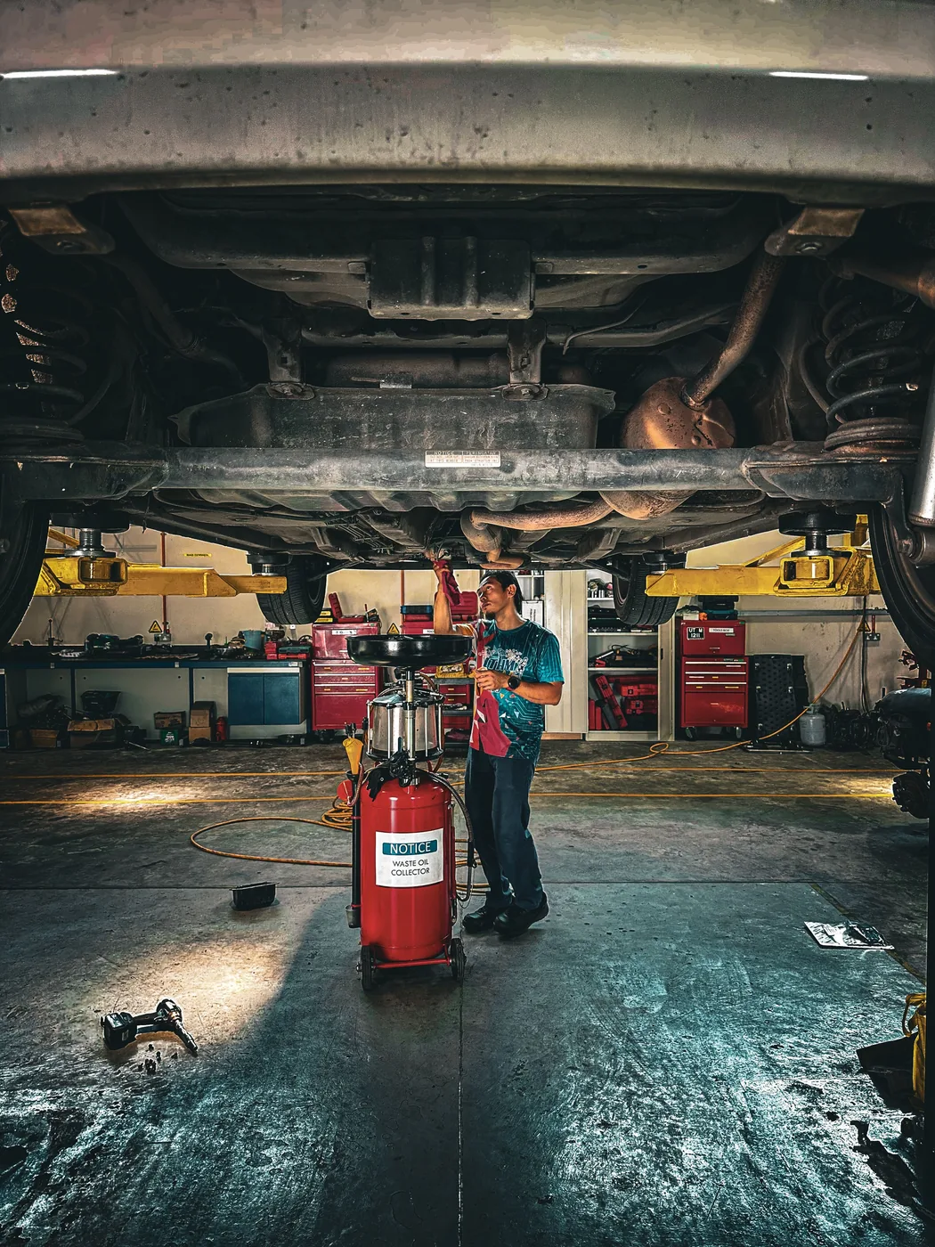 Mechaniker arbeitet unter einem Fahrzeug auf einer Hebebühne